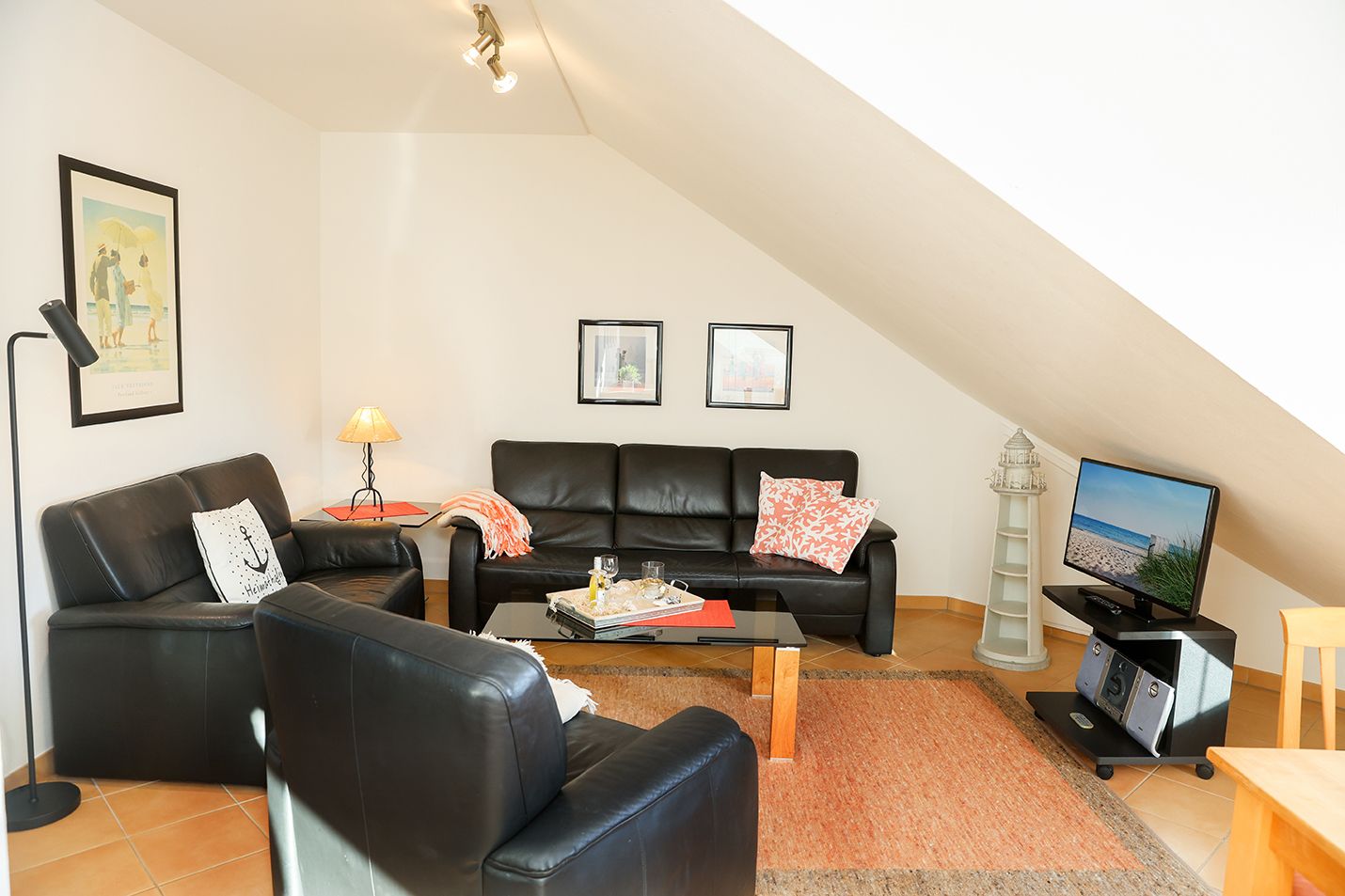 Wohnzimmer mit schwarzem Ledersofa unter Dachschräge