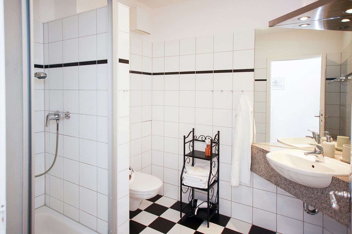 Badezimmer mit weißen Fliesen und Handtuchregal